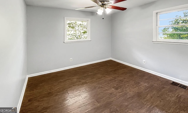 empty room featuring dark wood-type flooring, ceiling fan, and a healthy amount of sunlight