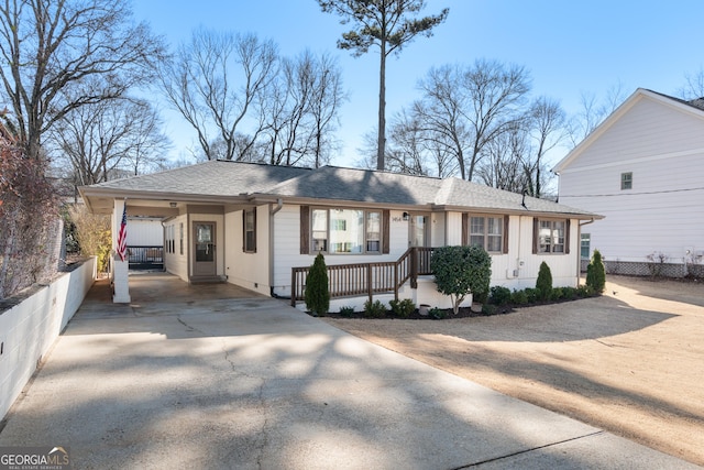 single story home featuring concrete driveway, a shingled roof, and an attached carport