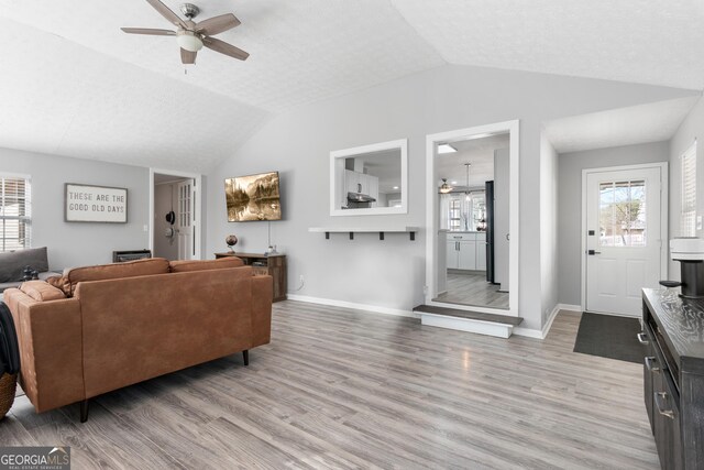 living room featuring light hardwood / wood-style flooring, plenty of natural light, an AC wall unit, and ceiling fan