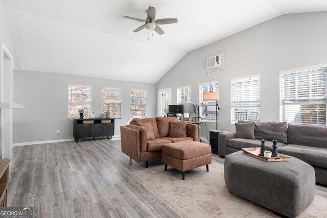 living room with a wealth of natural light, vaulted ceiling, heating unit, and light wood-type flooring