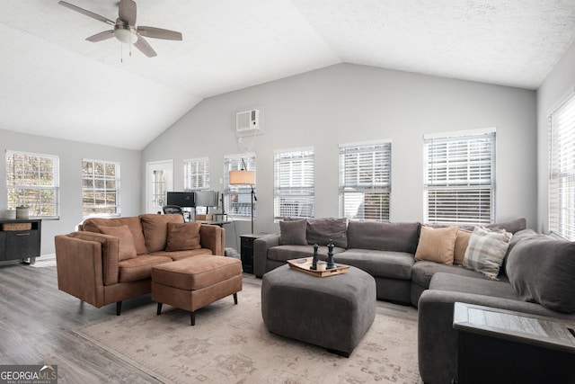 living area with a ceiling fan, a healthy amount of sunlight, vaulted ceiling, and light wood-style flooring