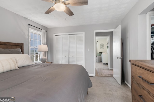 bedroom with light carpet, a ceiling fan, baseboards, and a closet