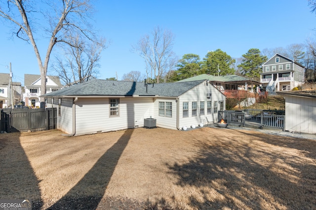 back of property with a yard, roof with shingles, and fence