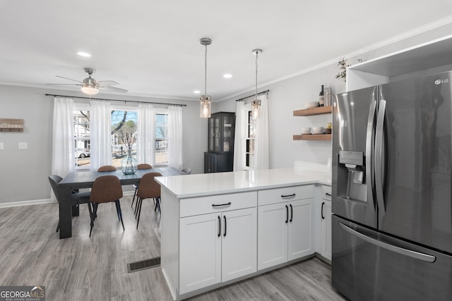 kitchen featuring a peninsula, light countertops, stainless steel fridge with ice dispenser, open shelves, and crown molding