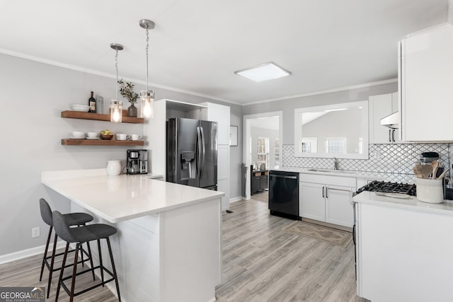 kitchen with white cabinetry, dishwasher, stainless steel fridge, a kitchen breakfast bar, and hanging light fixtures