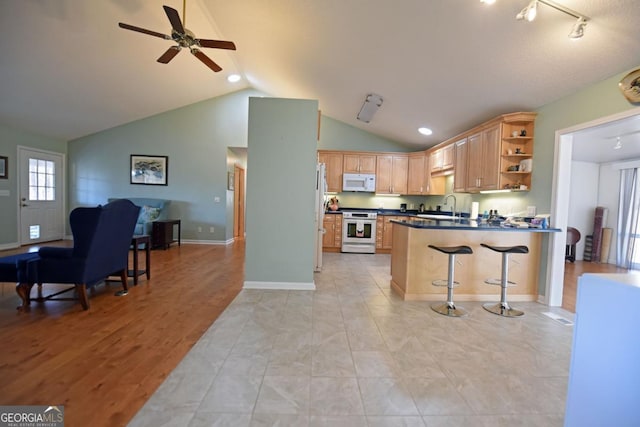 kitchen with a breakfast bar, sink, vaulted ceiling, kitchen peninsula, and white appliances