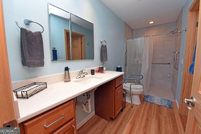 bathroom with hardwood / wood-style flooring, vanity, curtained shower, and toilet