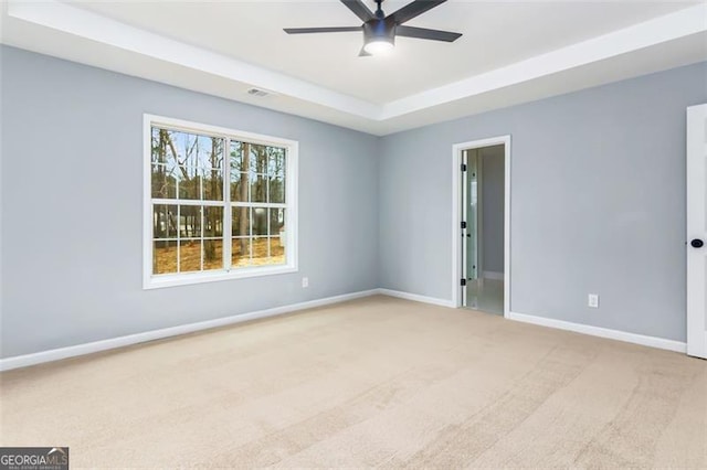 carpeted empty room featuring a raised ceiling and ceiling fan