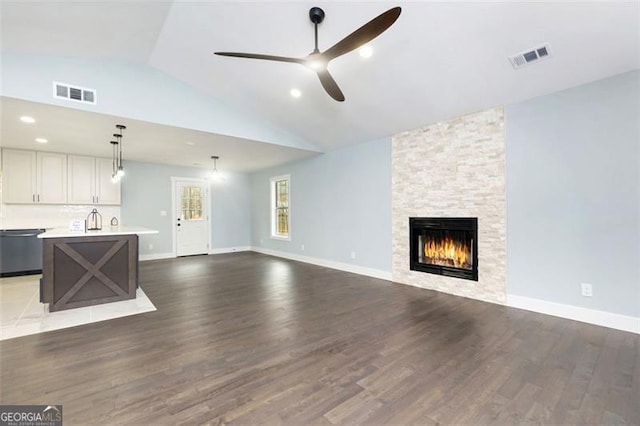 unfurnished living room featuring vaulted ceiling, hardwood / wood-style floors, ceiling fan, and a fireplace