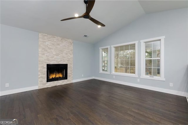 unfurnished living room with dark wood-type flooring, ceiling fan, a stone fireplace, and vaulted ceiling