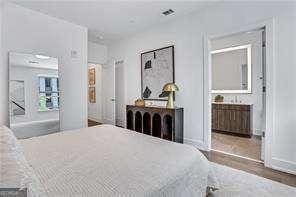 bedroom with ensuite bath and dark hardwood / wood-style floors