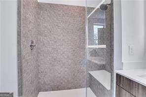 bathroom featuring a tile shower and vanity