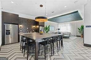 kitchen with dark brown cabinetry, stainless steel fridge, a breakfast bar, and light parquet floors