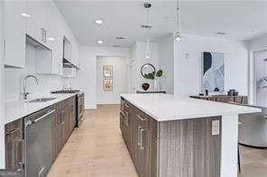 kitchen with pendant lighting, sink, stainless steel stove, white cabinets, and a kitchen island