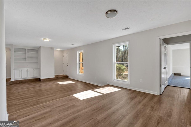 unfurnished living room with dark wood-type flooring and a textured ceiling