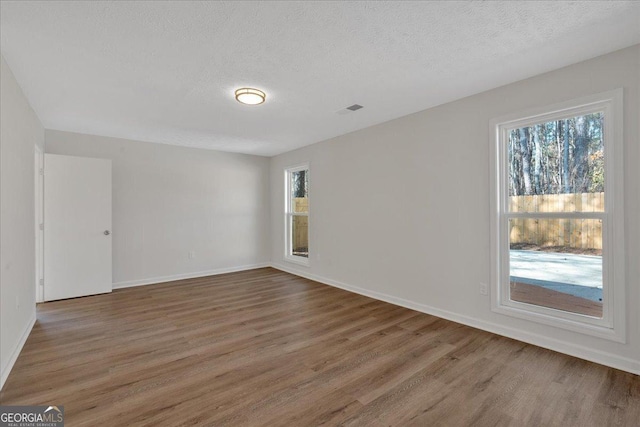 unfurnished room with a textured ceiling and dark hardwood / wood-style flooring