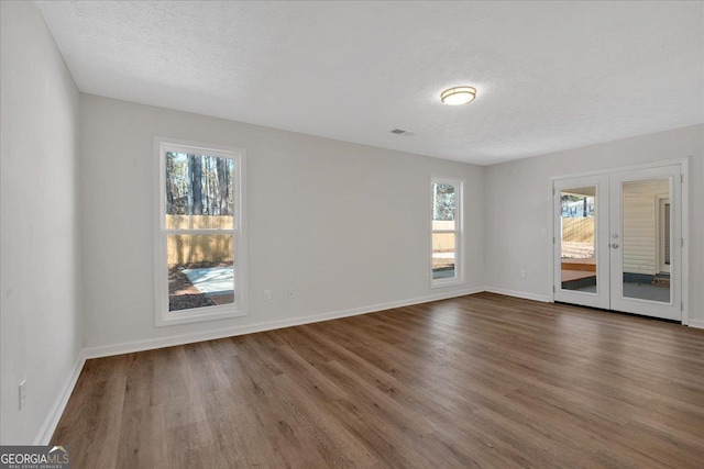 empty room featuring dark hardwood / wood-style flooring, french doors, and a textured ceiling