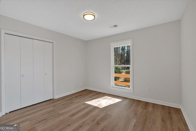 unfurnished bedroom with a closet and light wood-type flooring