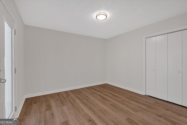 unfurnished bedroom with a closet, a textured ceiling, and light wood-type flooring