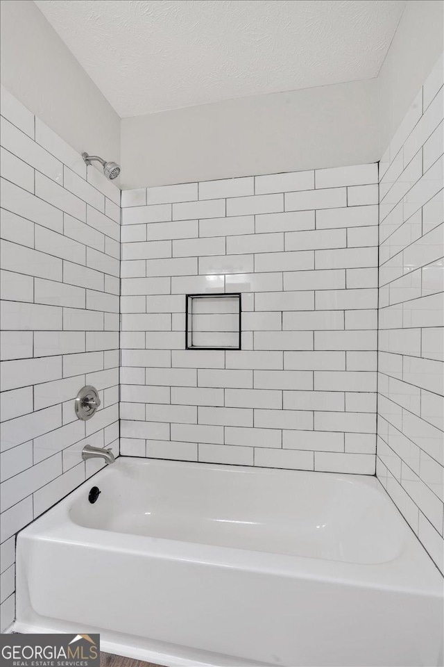 bathroom featuring tiled shower / bath combo and a textured ceiling