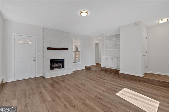 unfurnished living room with a fireplace and light wood-type flooring