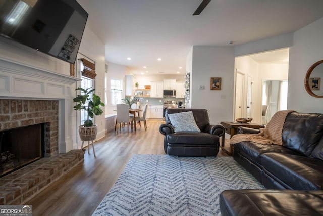 living room featuring a brick fireplace and light hardwood / wood-style flooring