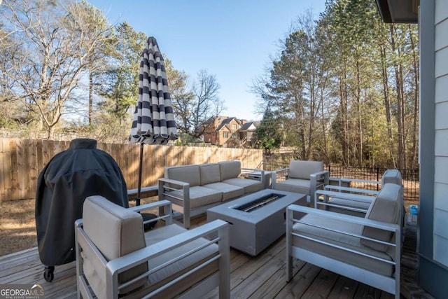 wooden terrace featuring area for grilling and an outdoor living space with a fire pit