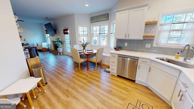 kitchen with sink, white cabinetry, tasteful backsplash, light wood-type flooring, and stainless steel dishwasher