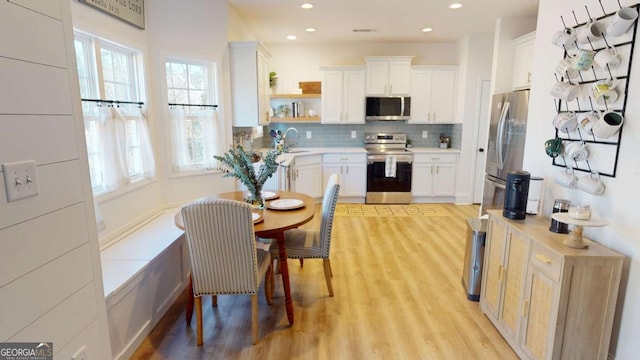 kitchen featuring sink, white cabinetry, stainless steel appliances, light hardwood / wood-style floors, and decorative backsplash