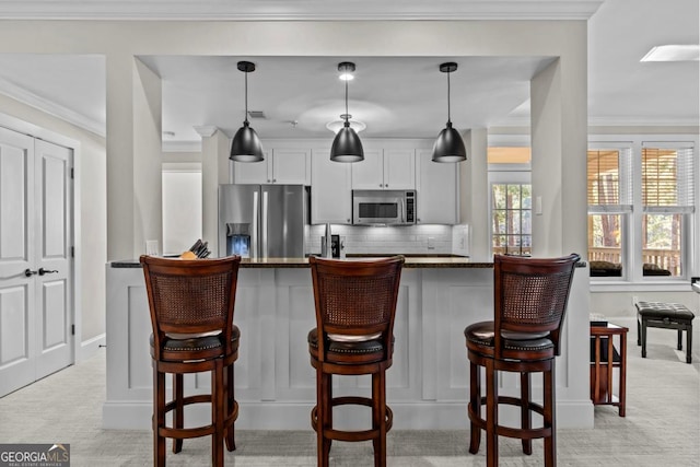 kitchen with dark stone countertops, decorative light fixtures, white cabinetry, and appliances with stainless steel finishes