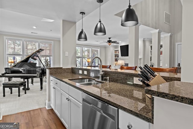 kitchen with sink, white cabinetry, decorative light fixtures, stainless steel dishwasher, and dark stone counters