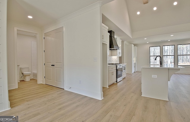 kitchen featuring a center island with sink, custom range hood, white cabinets, a kitchen bar, and stainless steel range with gas cooktop