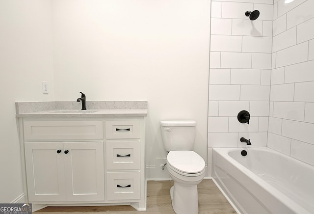 full bathroom with vanity, tiled shower / bath, wood-type flooring, and toilet