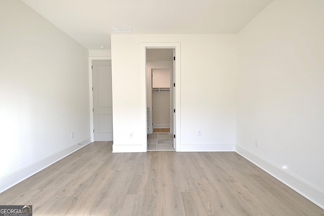 unfurnished bedroom with a walk in closet, light hardwood / wood-style floors, and a closet