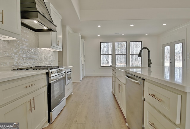 kitchen featuring appliances with stainless steel finishes, tasteful backsplash, light hardwood / wood-style floors, light stone countertops, and custom range hood