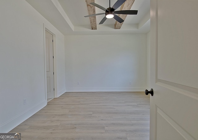 unfurnished room with ceiling fan, light hardwood / wood-style floors, and a tray ceiling