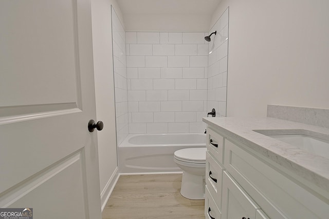 full bathroom featuring tiled shower / bath, hardwood / wood-style floors, vanity, and toilet