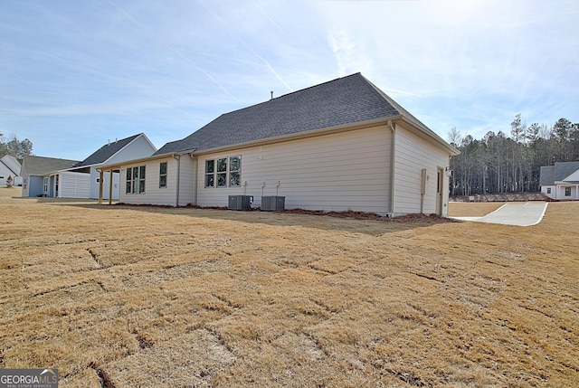 rear view of house featuring a yard and central air condition unit