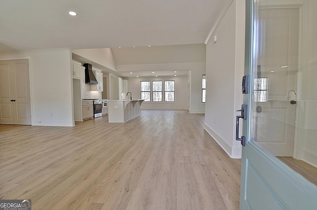 unfurnished living room featuring vaulted ceiling, sink, and light hardwood / wood-style flooring