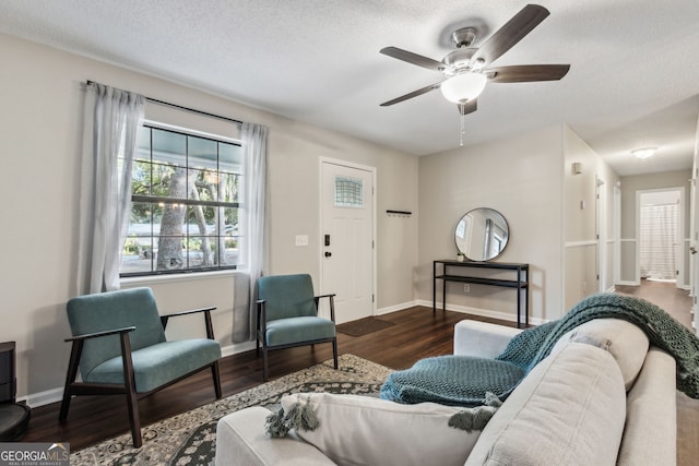 living room with ceiling fan, dark wood-type flooring, and a textured ceiling