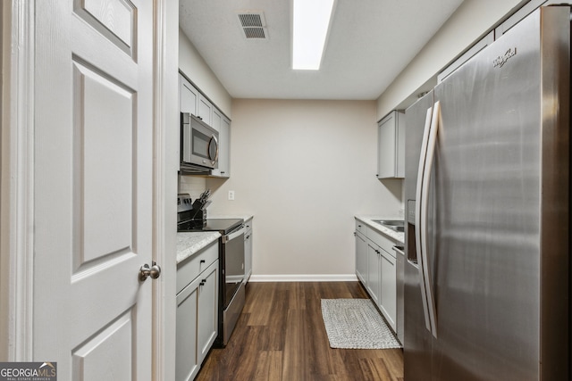 kitchen featuring dark wood-type flooring, appliances with stainless steel finishes, and gray cabinets