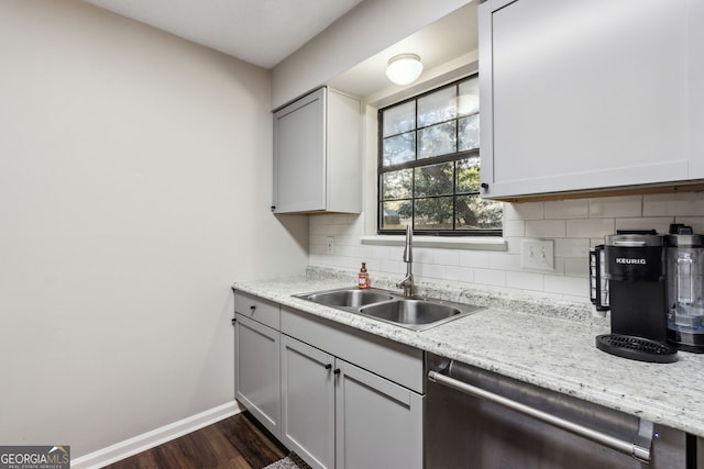 kitchen with sink, dishwasher, backsplash, light stone counters, and dark hardwood / wood-style flooring