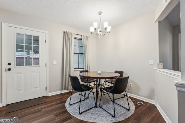 dining area featuring an inviting chandelier, dark hardwood / wood-style floors, and a textured ceiling