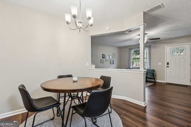 dining area with dark hardwood / wood-style floors, ceiling fan with notable chandelier, and a textured ceiling