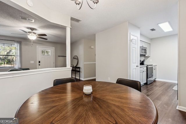 dining area with ceiling fan, dark hardwood / wood-style flooring, and a textured ceiling