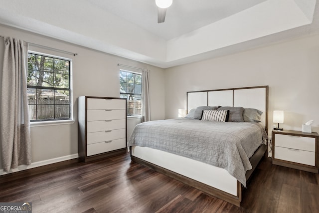 bedroom featuring dark wood-type flooring, ceiling fan, and a tray ceiling