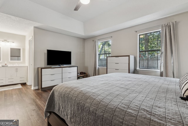 bedroom featuring dark hardwood / wood-style flooring, ceiling fan, and ensuite bathroom