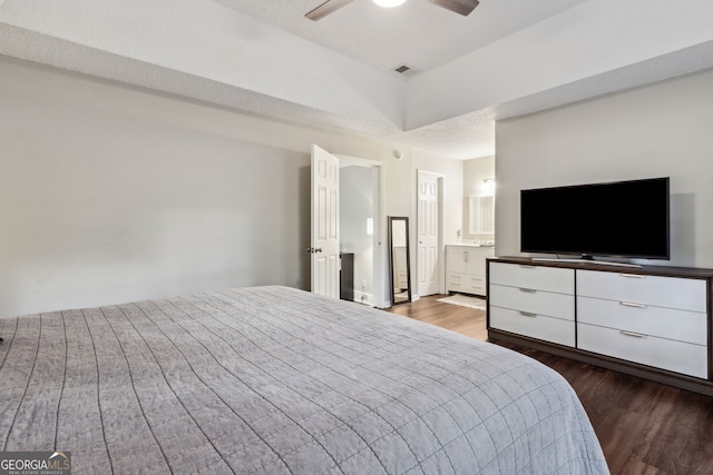 bedroom featuring hardwood / wood-style flooring, ensuite bath, ceiling fan, and a textured ceiling