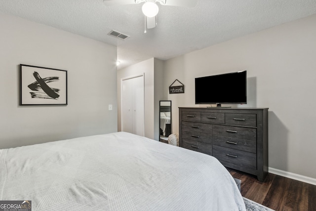 bedroom featuring ceiling fan, a textured ceiling, dark hardwood / wood-style flooring, and a closet