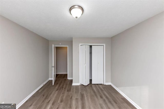 unfurnished bedroom with hardwood / wood-style flooring, a closet, and a textured ceiling